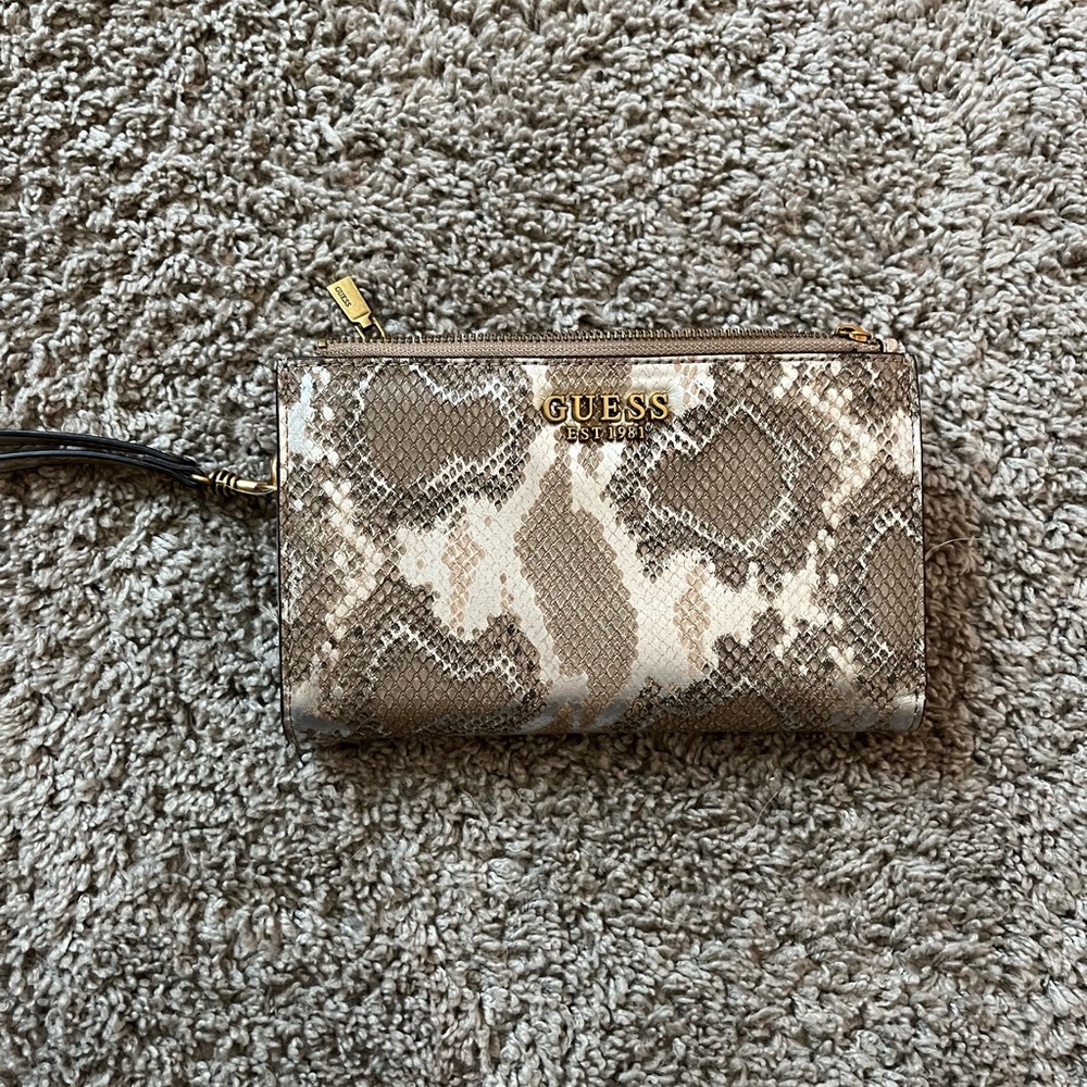 A Guess wallet that has a snake like pattern and is silver and mixes of browns.